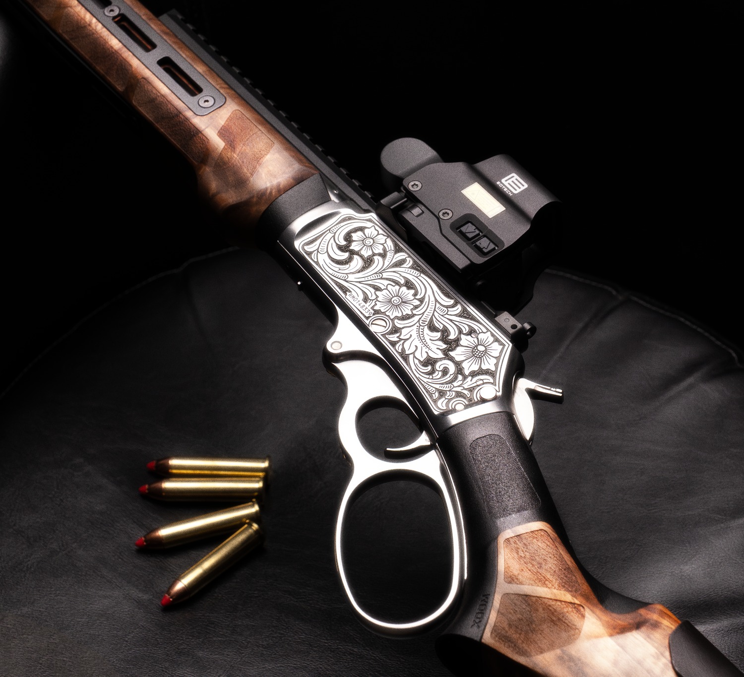 Close-up of engraved stainless receiver and lever on a lever-action rifle with rounds nearby