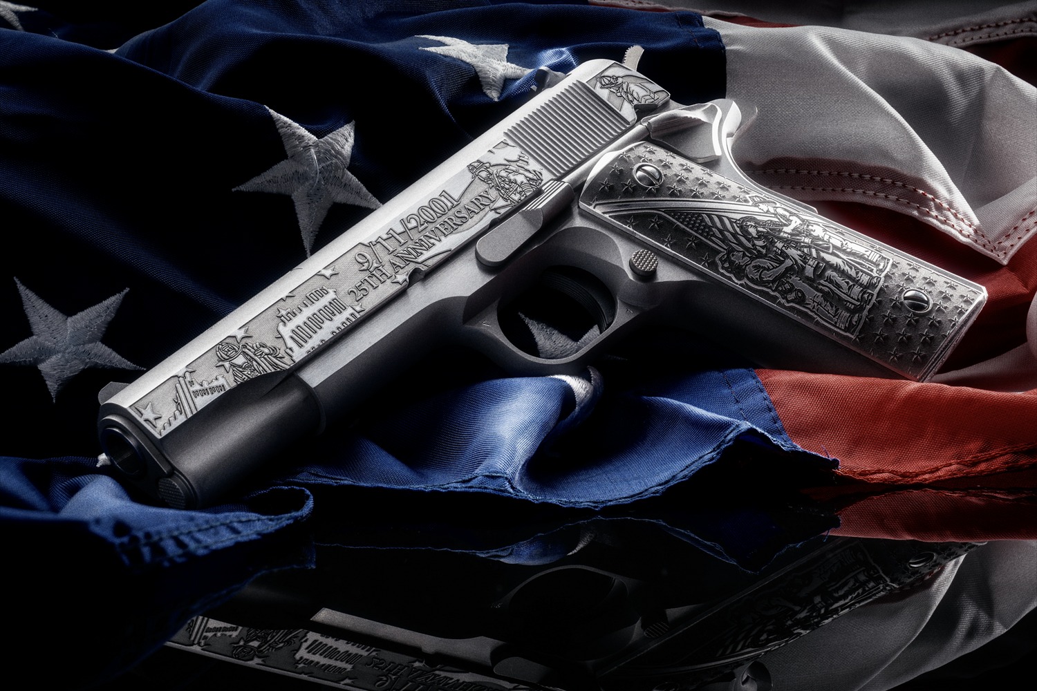 Engraved 1911 pistol resting on an American flag, showing the 9/11 anniversary slide engraving